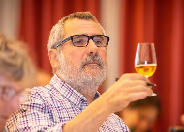 Un homme examine la couleur d'un verre de cidre